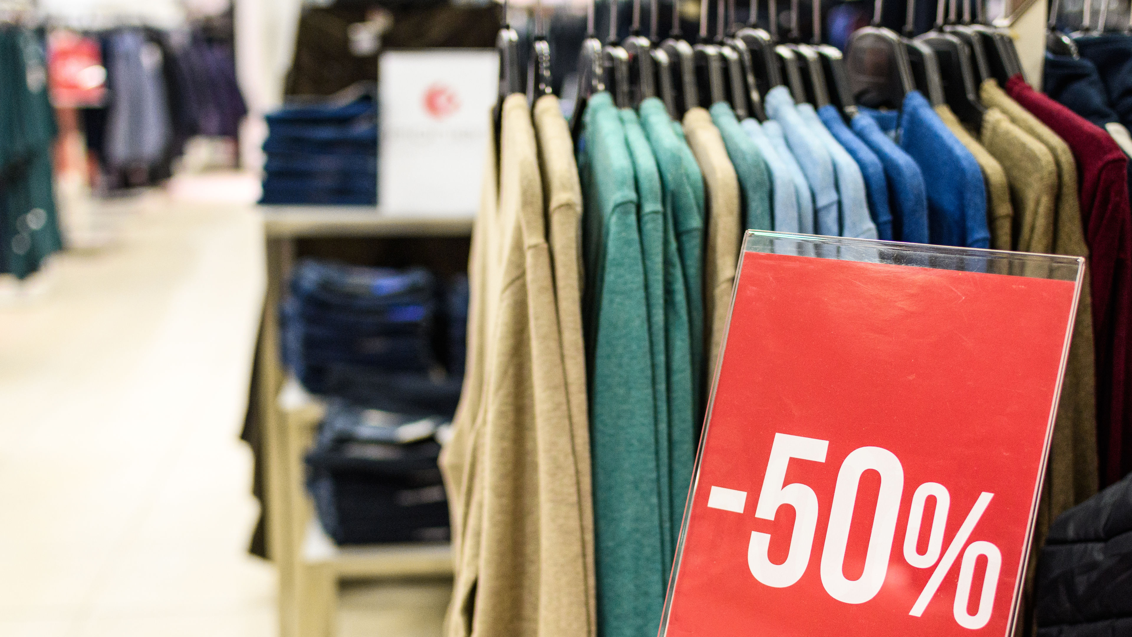 A clothing rack with a red sign offering a 50%.  