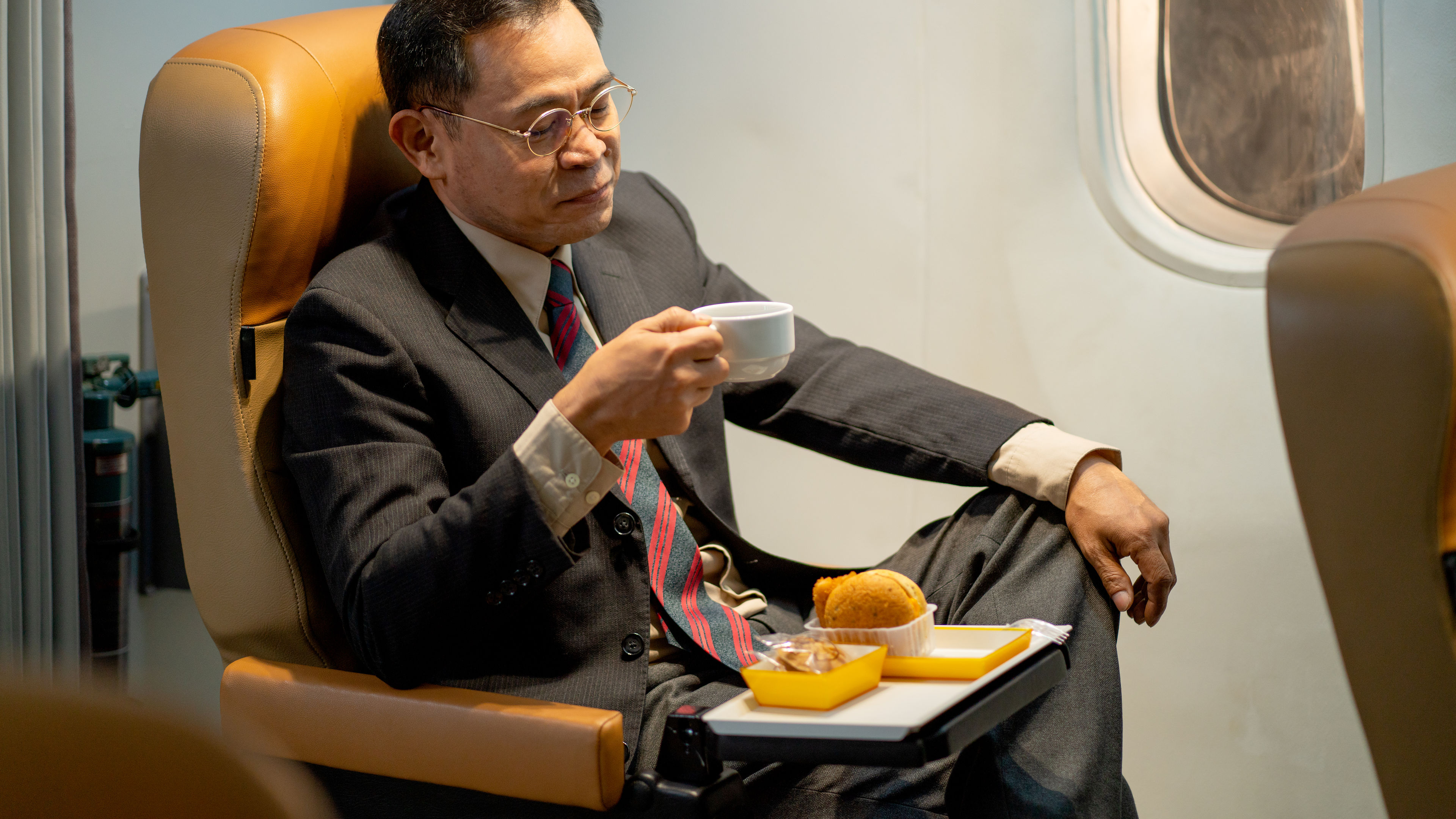 A businessman in a suit is seated comfortably in an airplane
