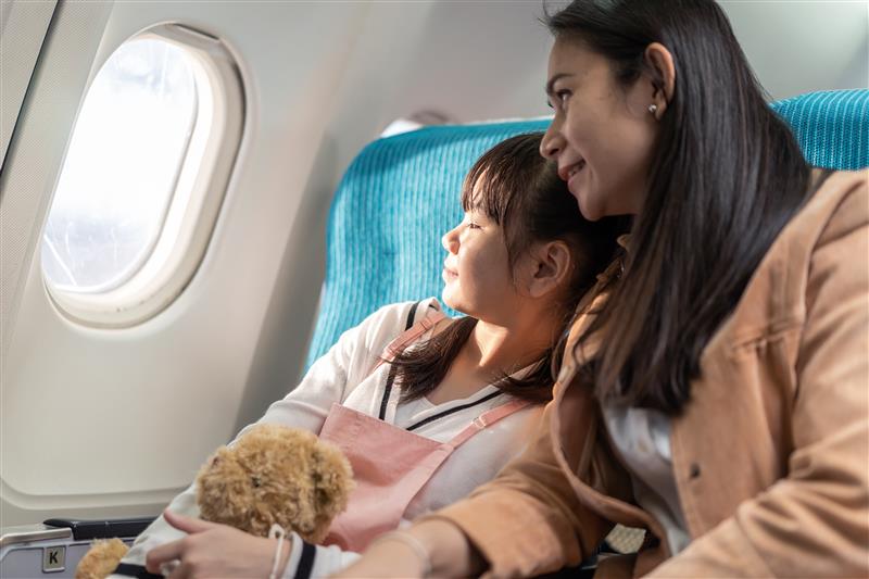 A mom and her child in a flight looking at the window. 
