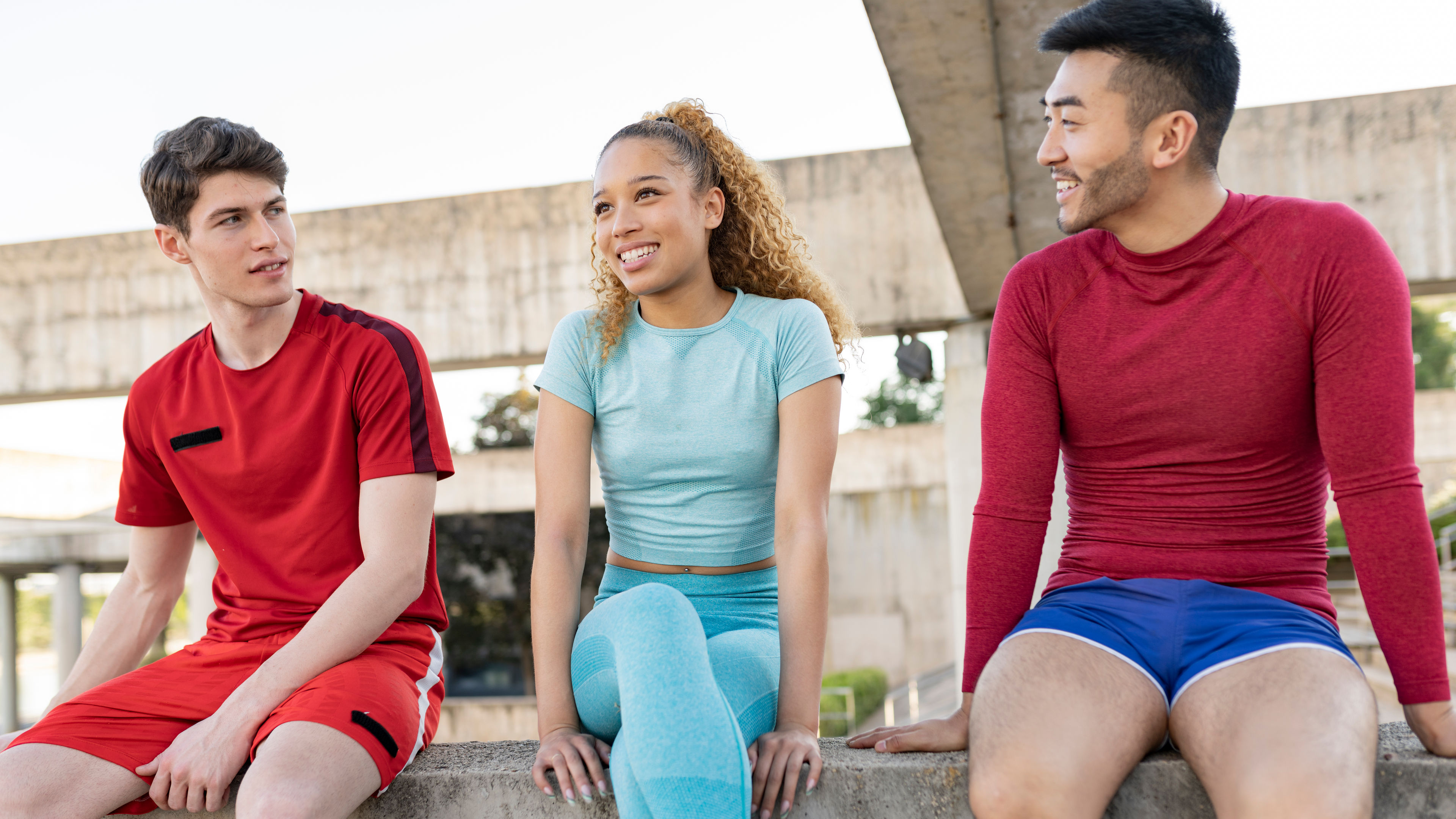 A young group of multi-ethnic friends have a conversation outdoors