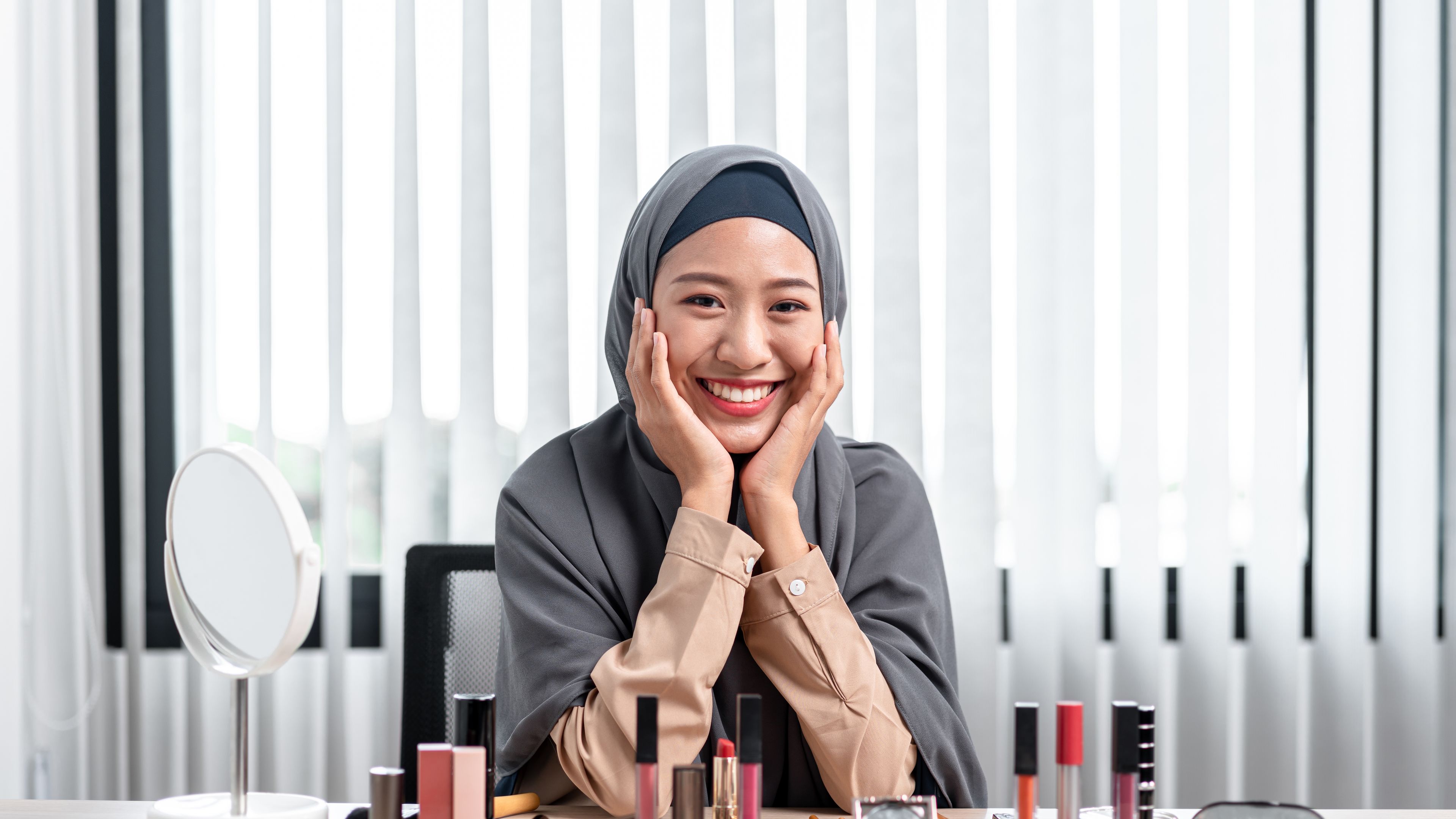 potret wanita Muslim Asia melihat kamera dan tersenyum sambil mengajar tutorial solek dalam talian secara langsung 