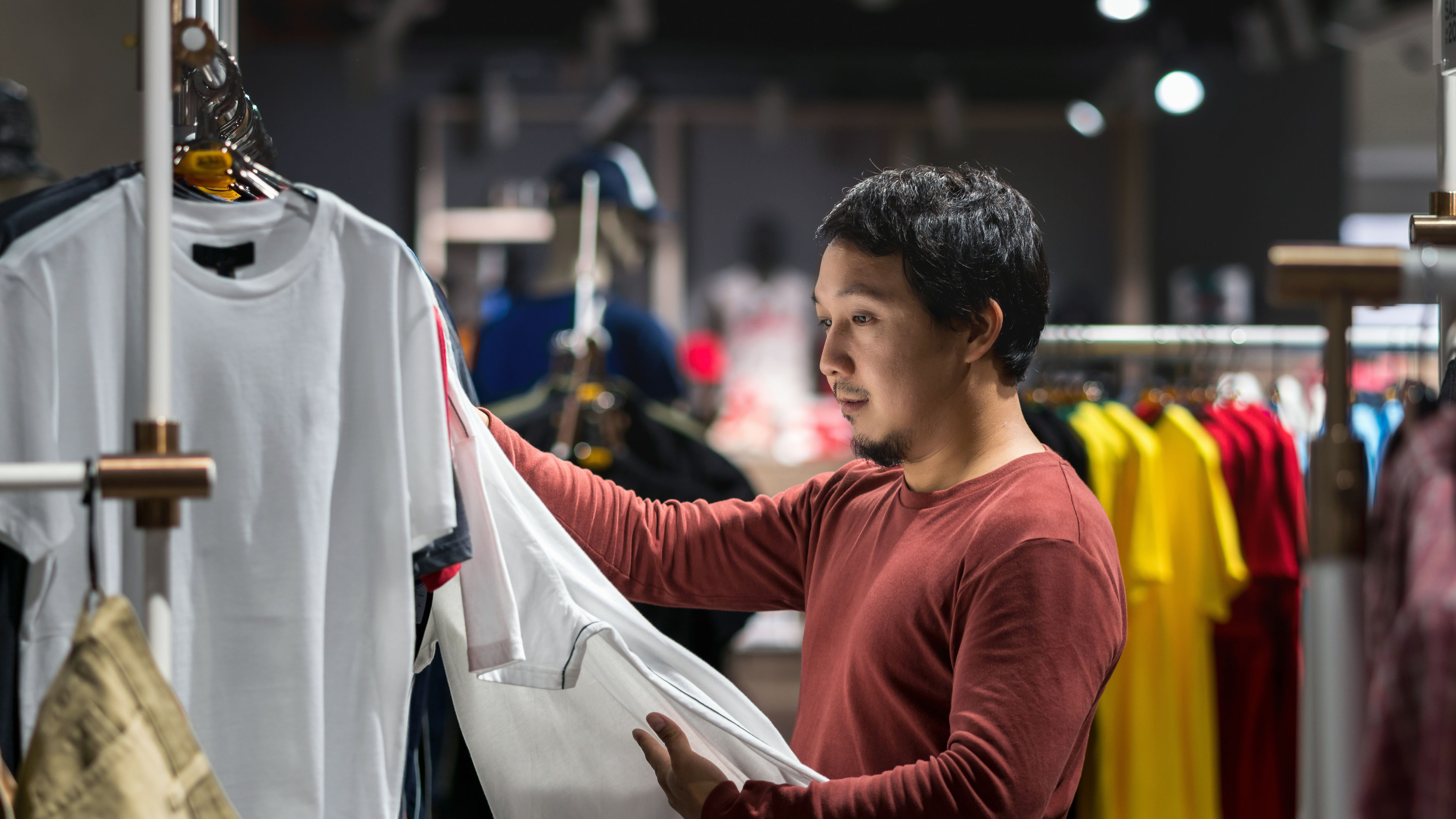 A smart Asian man  selecting of clothes in a clothing store    