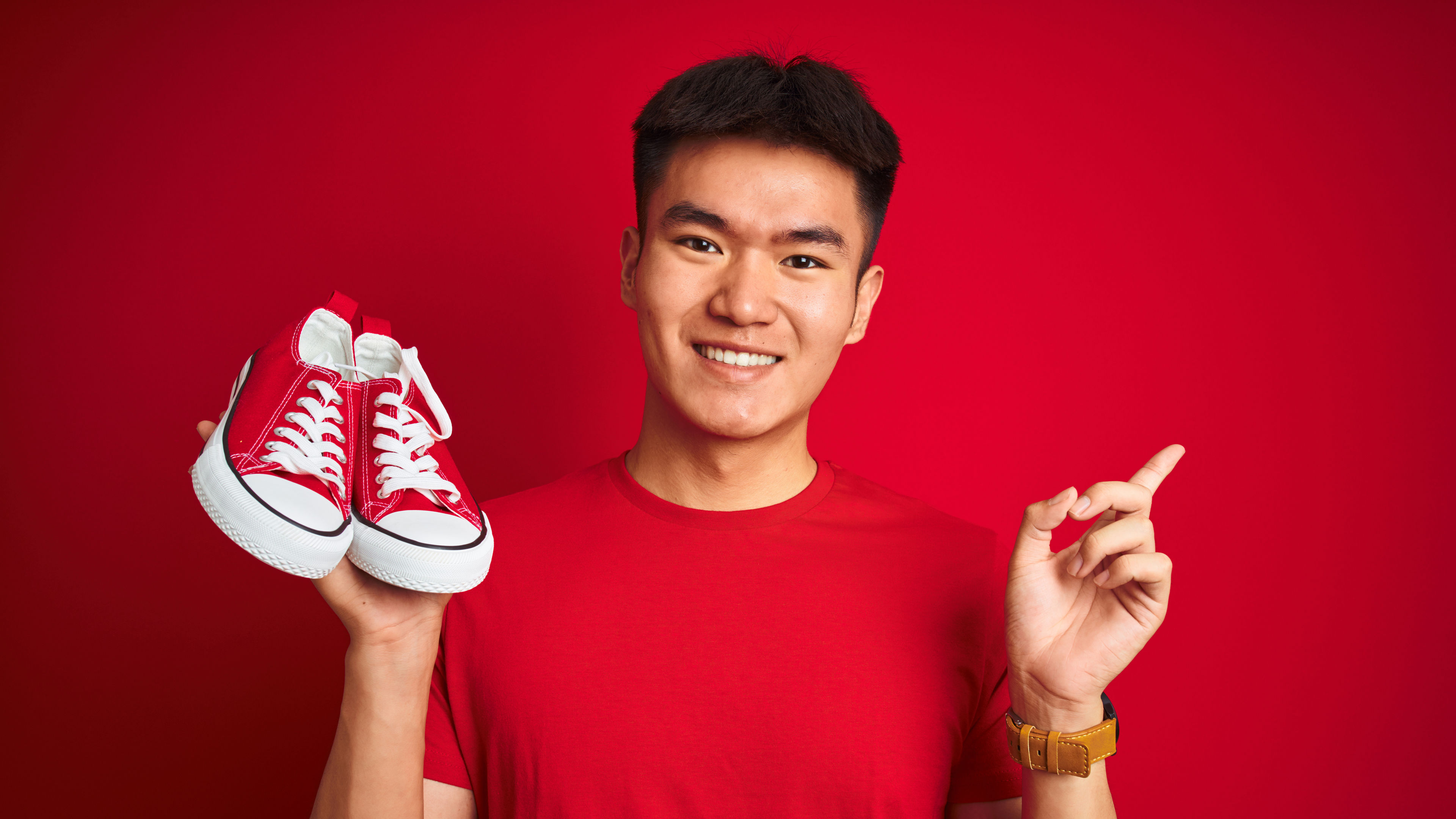 Smiling Man Holding a Pair of Red Sneakers