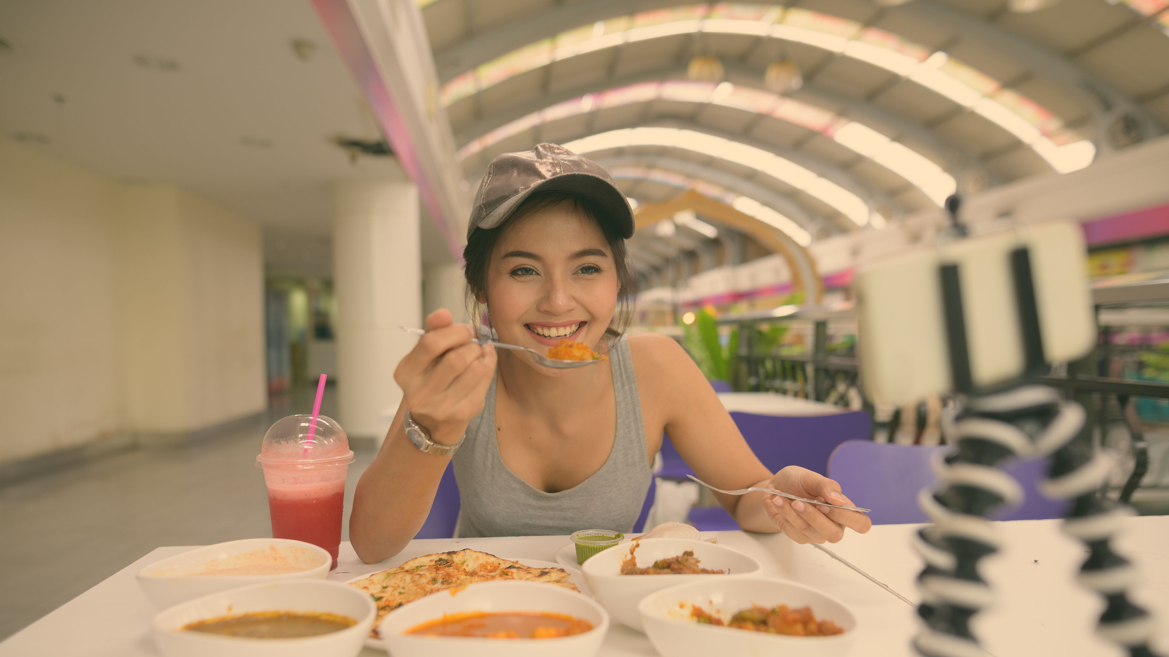 A cheerful woman enjoying a delicious meal while recording her food journey.