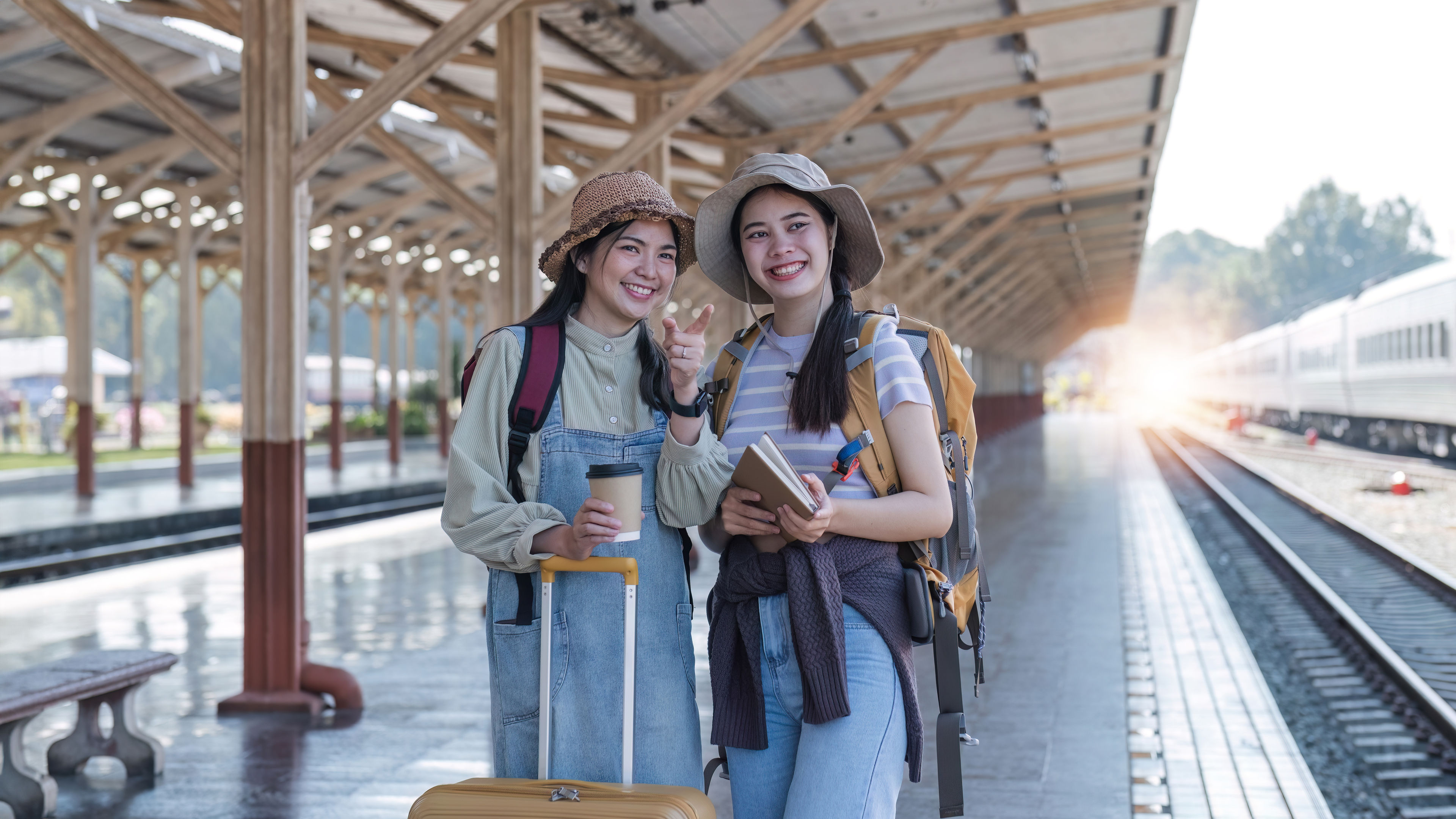 Two young women are standing on a train platform