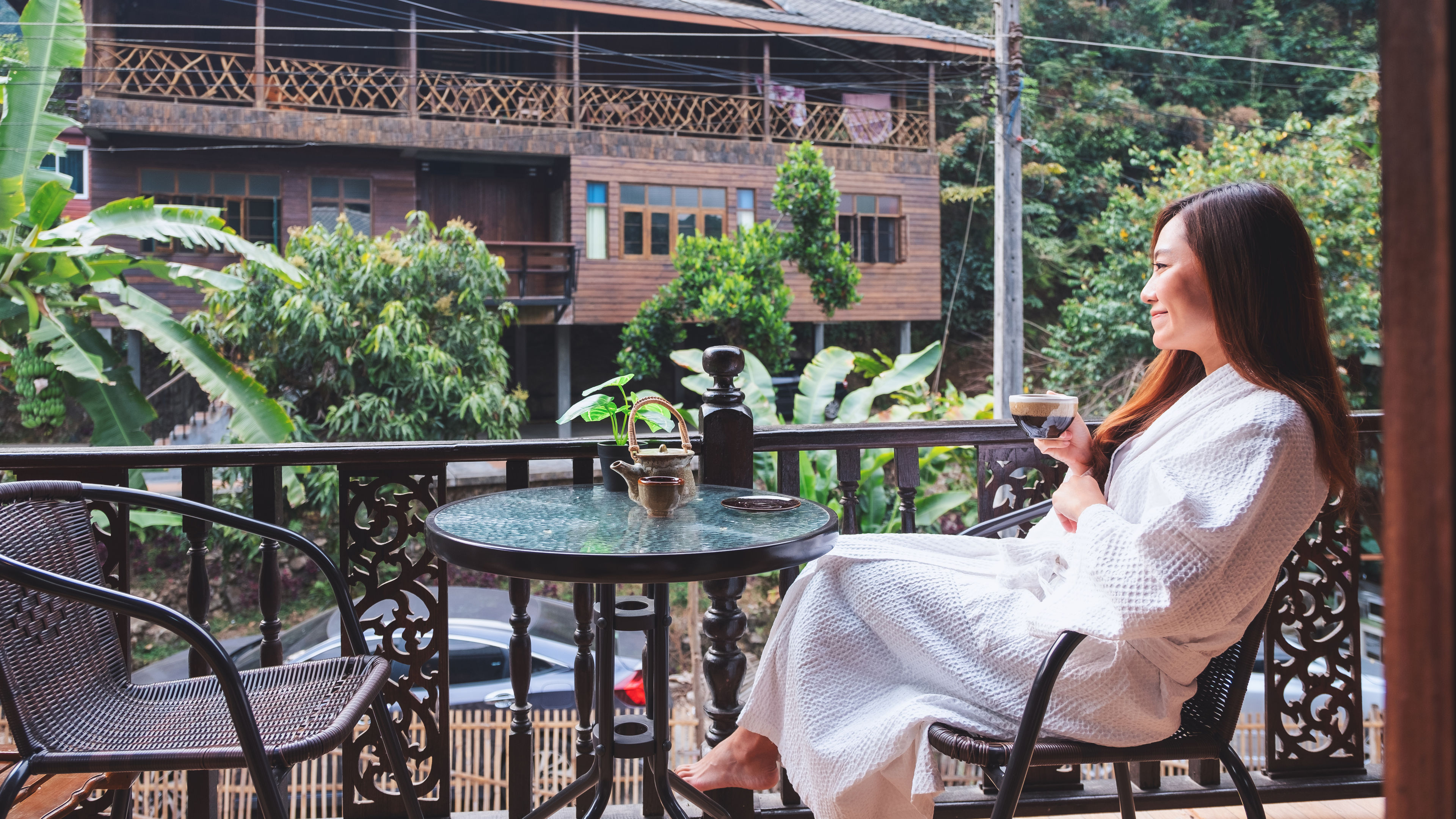 A woman is holding and drinking hot coffee in the morning while gazing at the view of the old town. 