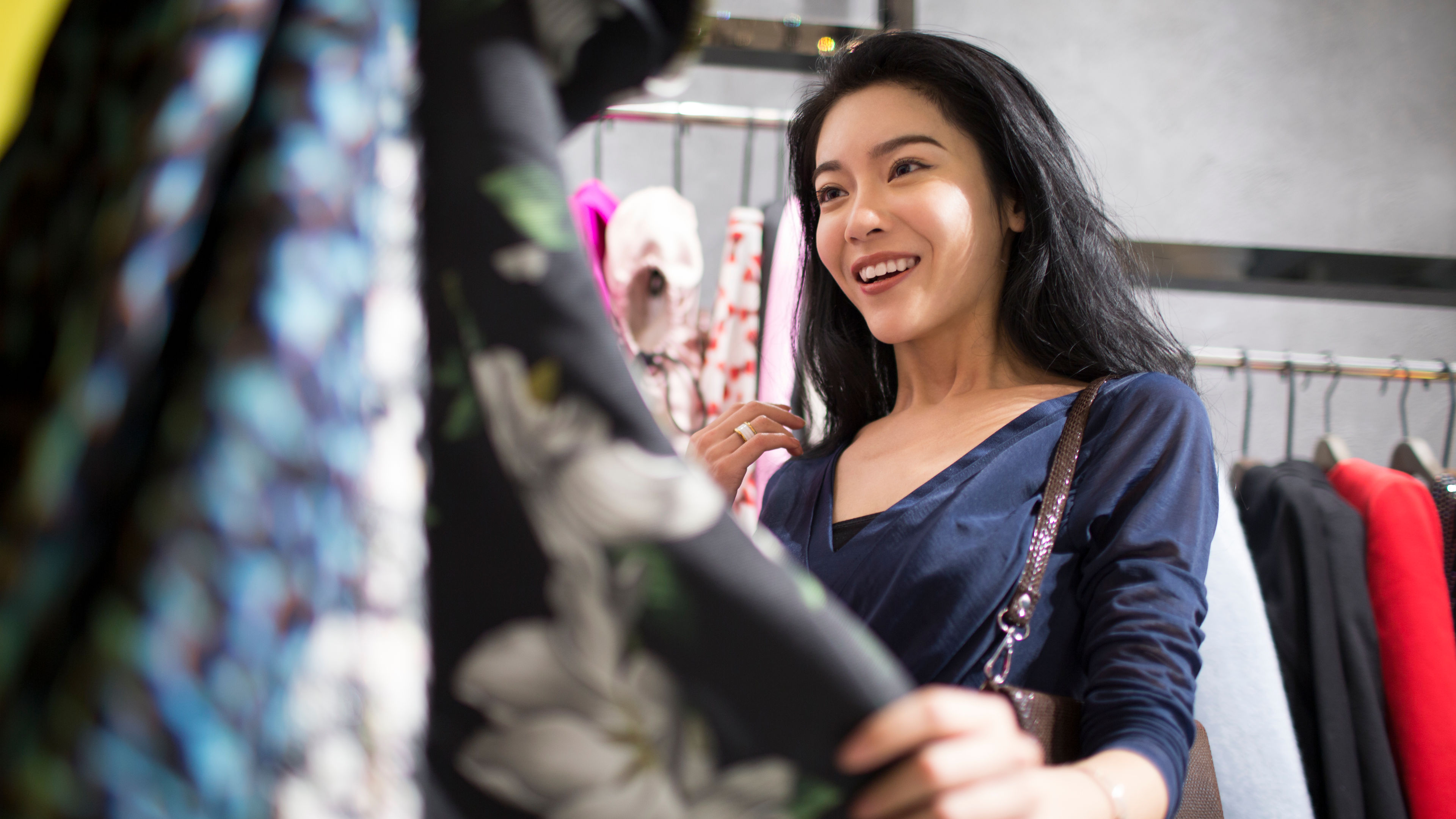 Young woman browsing stylish outfits in a vibrant clothing store, enjoying her shopping experience. 